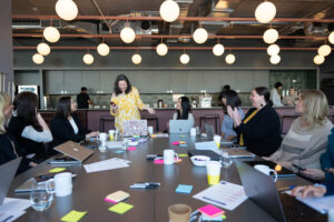 Clare standing presenting to women sitting around a board table