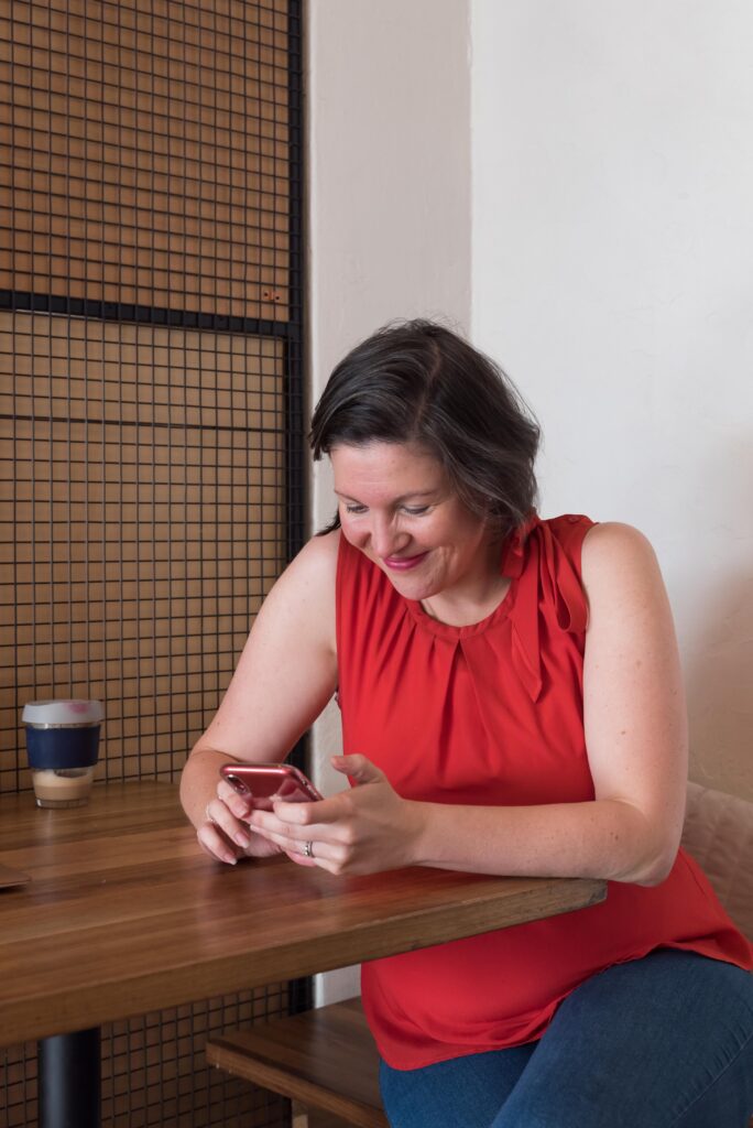 Clare texting on her mobile phone wearing a red top